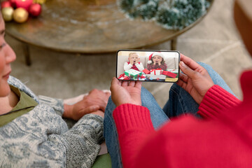 Wall Mural - Smiling diverse friends making smartphone christmas video call with two excited caucasian girls