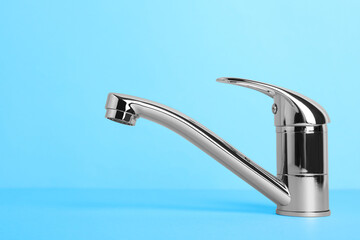 Single handle water tap on light blue background