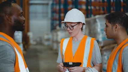 Wall Mural - Warehouse worker using a tablet checking inventory in a large warehouse distribution center. Caucasian female inspects cargo inventory.