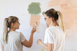 © BalanceFormCreative - Two female friends using paint roller to decorate walls in they new home.