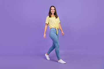 Poster - Full size photo of nice young brunette lady go wear yellow top jeans shoes isolated on purple color background