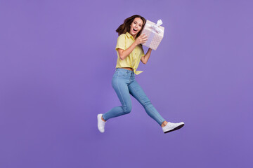 Canvas Print - Full length photo of impressed millennial brunette lady jump hold present wear yellow top jeans sneakers isolated on violet color background