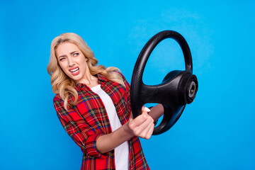 Wall Mural - Photo of upset shocked young lady wear plaid shirt holding steering wheel looking empty space isolated blue color background