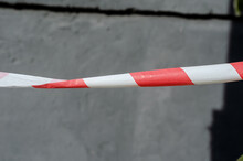 Red And White Barrier Tape Against The Gray Wall. Daytime, Outdo