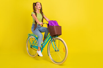 Poster - Full length body size view of attractive cheerful girl riding bike having fun isolated over bright yellow color background