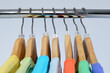 T-shirts of different colors hang on closing rack on wooden hangers with plastic size tags indexes of the XXS, XS, S, M, L, XL, XXL are isolated on white background