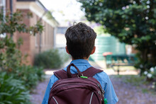 Young School Boy Walking Away From Camera, To Class
