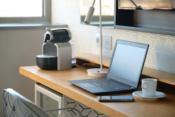 Working desk with laptop, smartphone and a cup of coffee in an hotel room.