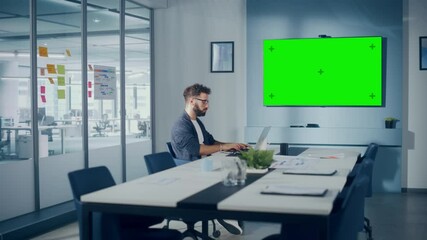 Leinwandbilder - Office Conference Meeting Room: Handsome Hispanic Specialist Working on Laptop Computer interacts with Green Screen Choma Key Wall TV. Businessperson Working in Growing e-Commerce Startup. Wide Shot