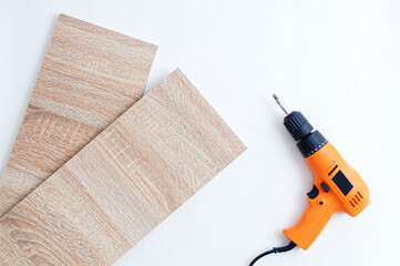 Two furniture pieces made of chipboard wood and an electric drill on  white background.