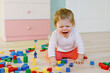 © Irina Schmidt - Upset crying baby girl with educational toys. Sad tired or hungry alone healthy child sitting near colorful different wooden blocks at home or nursery. Baby missing mother in daycare