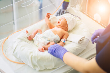 unrecognizable nurse in blue gloves takes action and care for premature baby, selective focus on bab