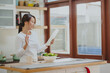 © interstid - Beautiful Asian woman greeting her friends via digital tablet in kitchen before eating salad vegetables