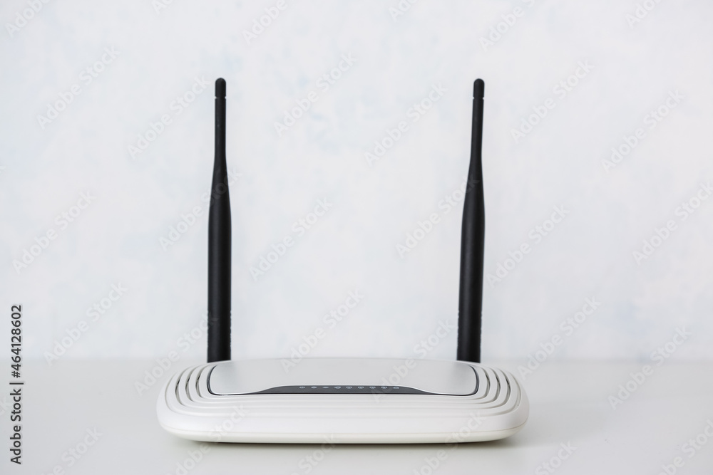 Modern wi-fi router on table near light wall
