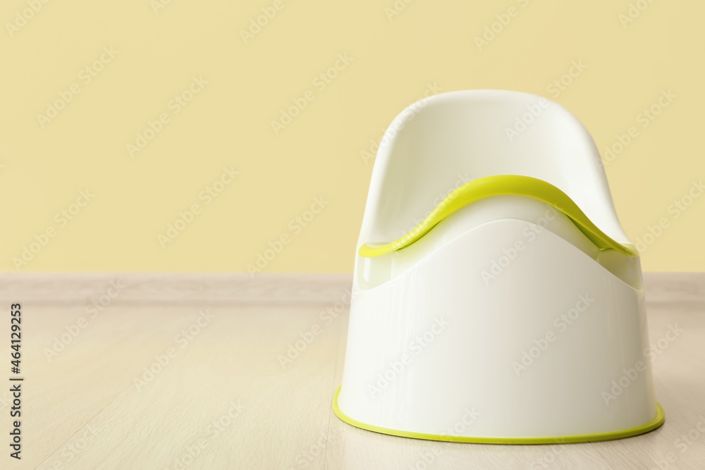 Potty on wooden floor near color wall