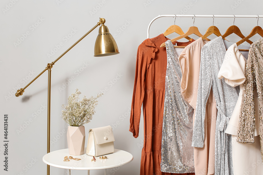 Rack with stylish clothes near light wall