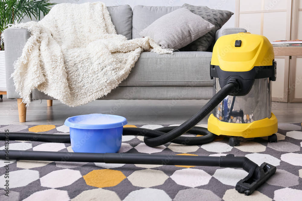 Vacuum cleaner with detergent in basin on carpet in room