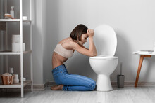 Young Woman Near Toilet Bowl In Bathroom. Anorexia Concept