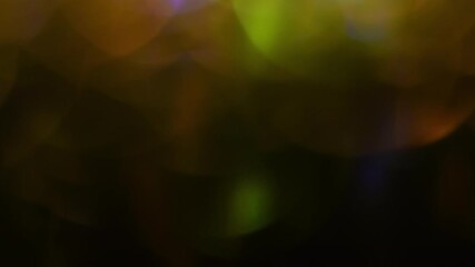 Wall Mural - Huge golden bokeh in a row shimmer from bottom to top on a black background. The line of yellow mixing circles moves up. Light leaks as background or overlay. Bokeh motion.