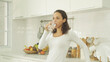© tampatra - Portrait of happy latin woman drinking a glass of water in kitchen at home. People lifestyle. Freshness.