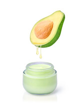 Avocado Fruit With Avocado Oil Drop Dripping To Glass Jar Of Beauty Skin Care Cream Isolated On White Background.