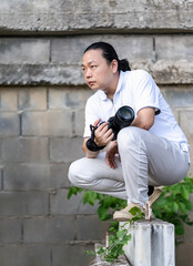 Wall Mural - Asian Professional cameraman sits and thinks about how to create a creativity photo in the construction area background and environment.