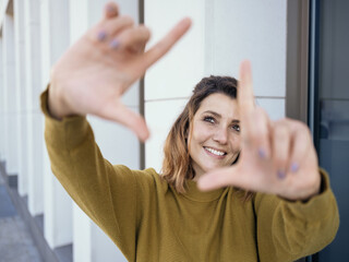 Creative young woman framing something on a street with fingers