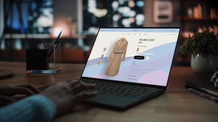 Close Up on Hands of a Female Using Laptop Computer with Clothing Online Web Store to Choose and Buy New Stylish Coat. Office Studio Apartment in the Evening with Big Windows.