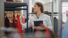 Clothing Store: Businesswoman And Visual Merchandising Specialist Uses Smartphone To Create Stylish Collection. Fashion Shop Sales Retail Manager Checks Stock. Small Business Owner And Designer Works