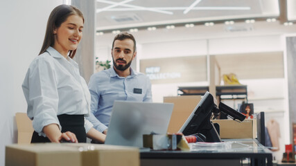 Clothing Store Checkout Cashier Counter: Female and Male Retail Sales Managers Carefully Packing Online Ordered Clothes into Boxes. Fashionable Shop, with Stylish Brand Designs Available on Internet