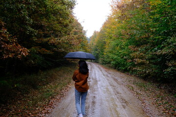 woman holding umbrella under rain in the forest