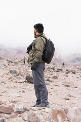 Poster - Vertical shot of the young man in the mountains, enjoying the fresh air and beautiful view.