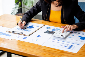 Close up Business woman using calculator and laptop for do math finance on wooden desk, tax, accounting, statistics and analytical research report concept