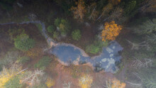 Aerial Top Down View To The Fog Cald Autumn Colored Woodland And Natural Emerald Blue Spring Lake And Stream