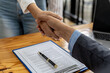 © kamiphotos - Two businesswomen shake hands after accepting a business proposal together, a handshake is a universal homage, often used in greeting or congratulations.