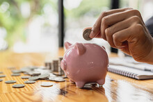 A Businessman Holding A Coin In A Piggy Bank. Placing Coins In A Row From Low To High Is Comparable To Saving Money To Grow More. The Concept Of Growing Savings And Saving By Investing In Stock Funds.