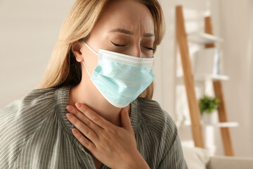 Wall Mural - Young woman in medical mask suffering from pain during breathing indoors