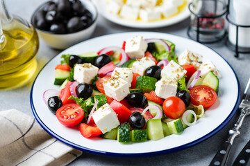 Wall Mural - Greek salad with black olives and feta cheese on plate with olive oil dressing, closeup view