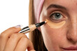 Young woman applyes concealer under her eyes