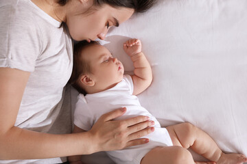 Canvas Print - Young mother resting near her sleeping baby on bed, top view. Space for text