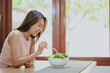 © interstid - Happy Asian woman eating healthy salad in white bowl on the table at home