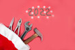 Flat composition with construction tools in santa claus hat on on a red background with 2022 lined with screw nuts. The concept of New Year and Christmas in the construction industry. 