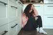 © gpointstudio - Young caucasian woman using mobile phone on kitchen floor