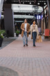 © LIGHTFIELD STUDIOS - full length of african american woman holding shopping bags and walking with happy boyfriend in coat in mall.