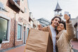 © LIGHTFIELD STUDIOS - happy african american woman taking selfie with boyfriend holding shopping bags.