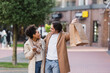 © LIGHTFIELD STUDIOS - amazed african american woman with smartphone looking at happy boyfriend holding shopping bags.