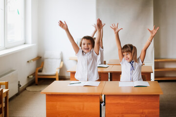 Wall Mural - The children of a classmate friend read together, solve problems. Mutual assistance at school, children sit studying at desks, school learning concept