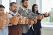 Close up of thumbs up business people showing gesture recommendation or good choice. Team shows satisfaction, gives a positive response and promises career growth. Blurred background. Selective focus.