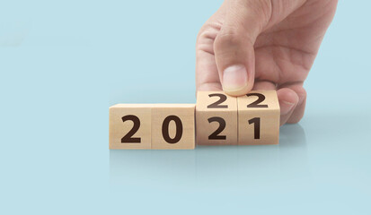 The hand puts  wooden cube with the letter  from the 2022 2021. wooden cubes standing  in hand