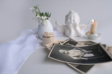 stack of vintage photos, baby photography of 1960, candle is lit, first spring flowers, snowdrop, Galanthus in vase, concept of family tree, genealogy, childhood memories